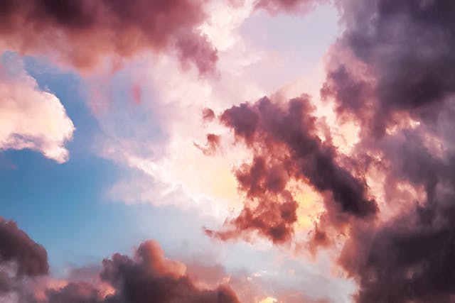 dramatic pink and dark grey clouds and white clouds with blue sky