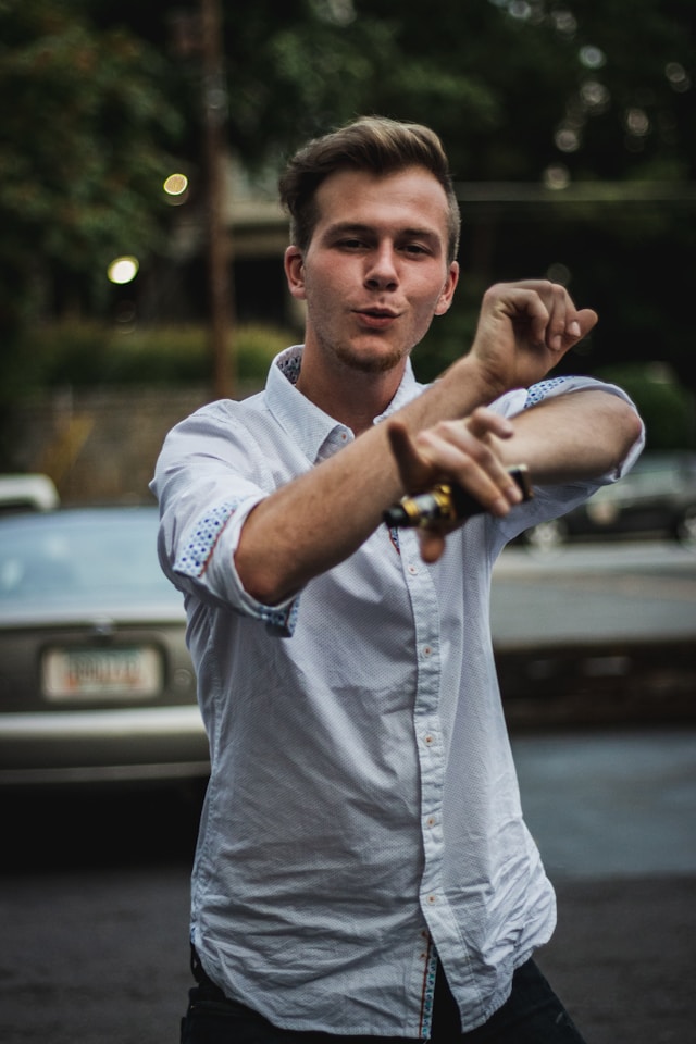 man in button-up shirt dances in street