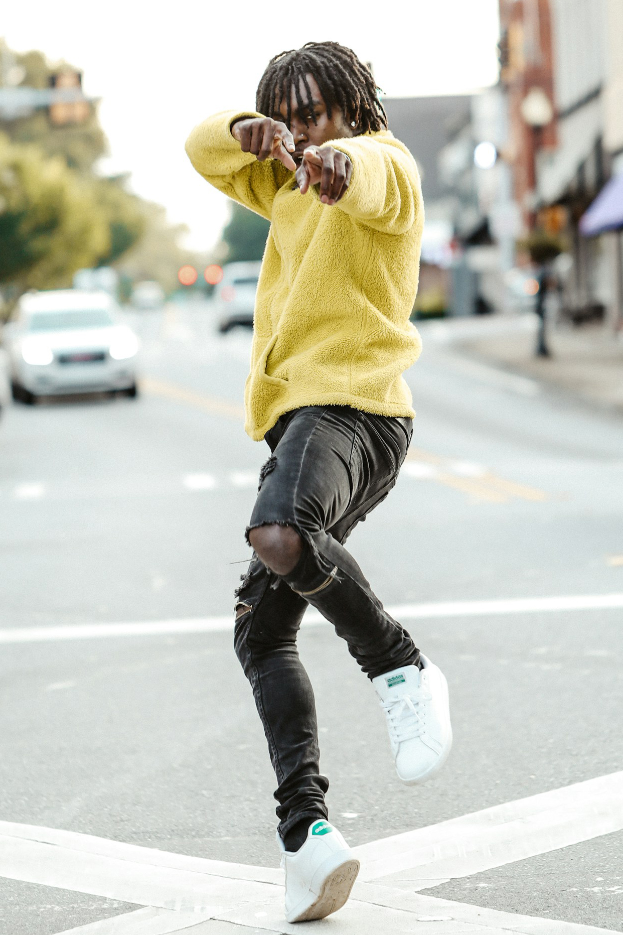 man in bright yellow sweatshirt dances in street
