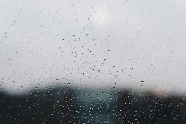 blurred lanscape through raindrops on window