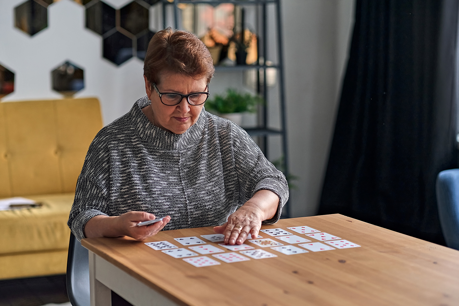 older woman seated at table playing solitaire